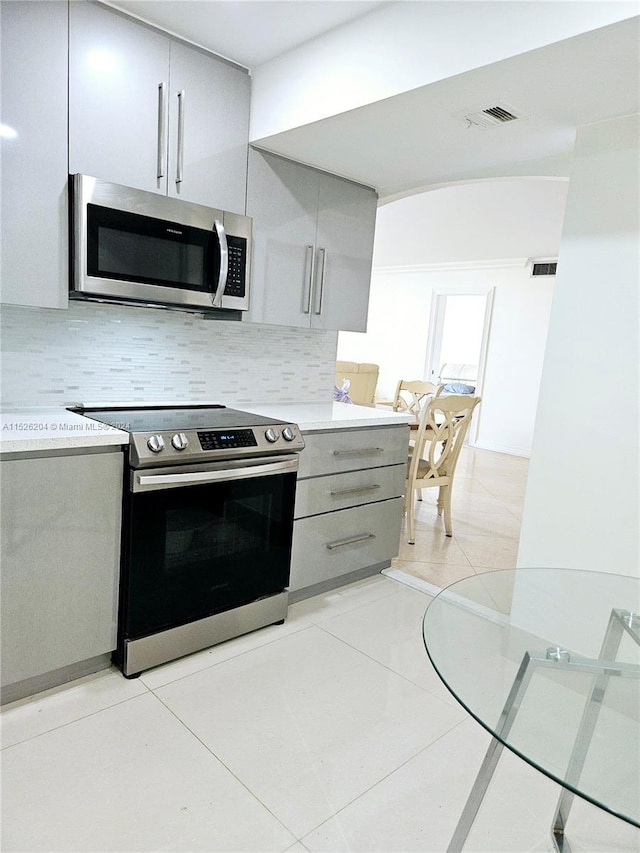 kitchen featuring backsplash, stainless steel appliances, and gray cabinets