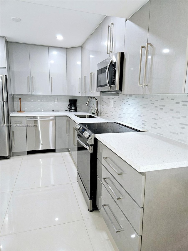 kitchen featuring tasteful backsplash, stainless steel appliances, sink, and light tile floors