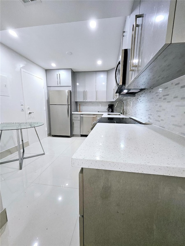 kitchen with a kitchen bar, sink, stainless steel appliances, light stone counters, and tasteful backsplash