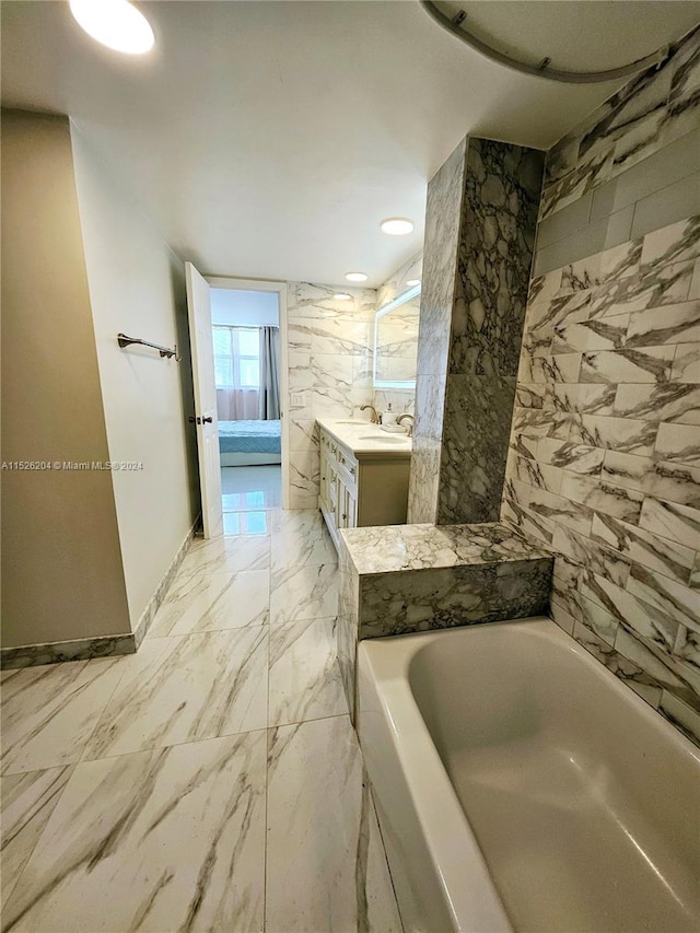 bathroom with vanity, tile flooring, a washtub, and tile walls