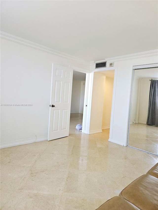 unfurnished room with ornamental molding and light tile floors