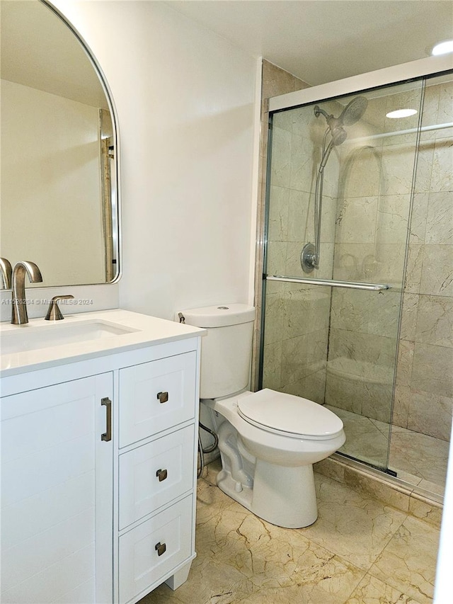 bathroom featuring a shower with door, tile flooring, large vanity, and toilet