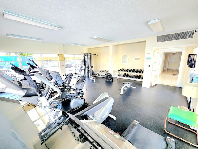 gym with a textured ceiling and tile flooring