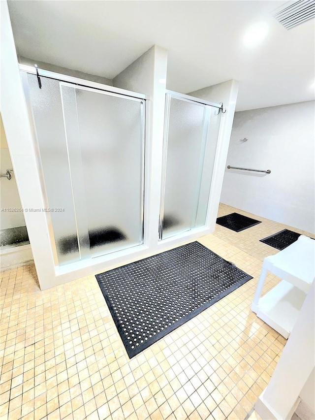 bathroom featuring a shower with door and tile flooring