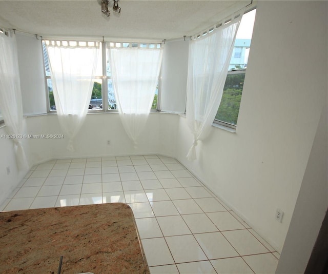 unfurnished room featuring light tile floors, a textured ceiling, and a wealth of natural light