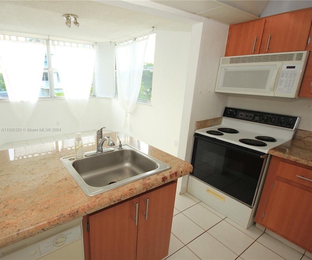 kitchen with plenty of natural light, white appliances, light tile flooring, and sink