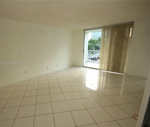 unfurnished room with light tile floors and a textured ceiling