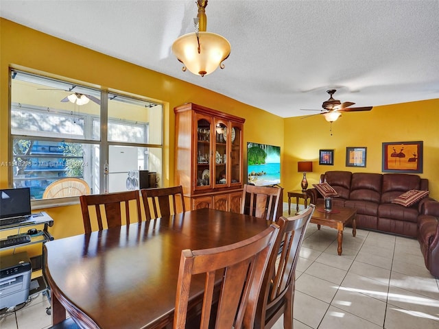 dining room featuring a textured ceiling, ceiling fan, and light tile floors