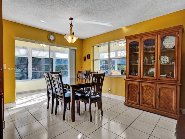 tiled dining space featuring plenty of natural light, a textured ceiling, and ceiling fan