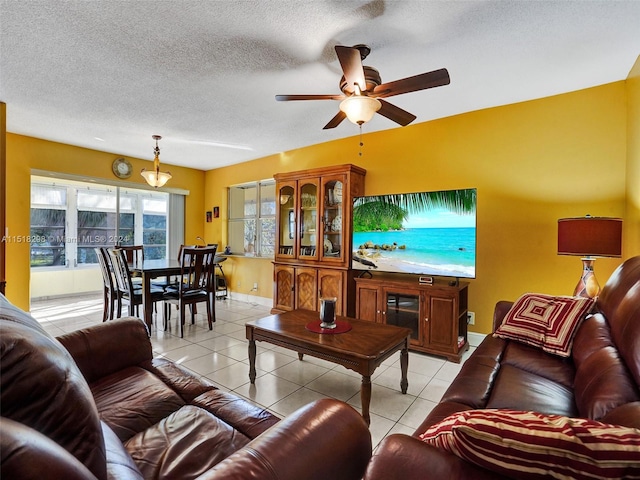 tiled living room featuring a water view, ceiling fan, and a textured ceiling