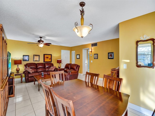 dining area featuring a textured ceiling, ceiling fan, and light tile flooring