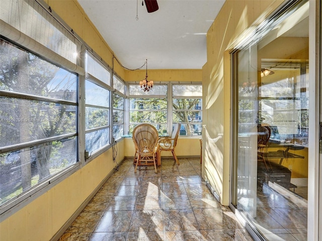 sunroom with ceiling fan with notable chandelier