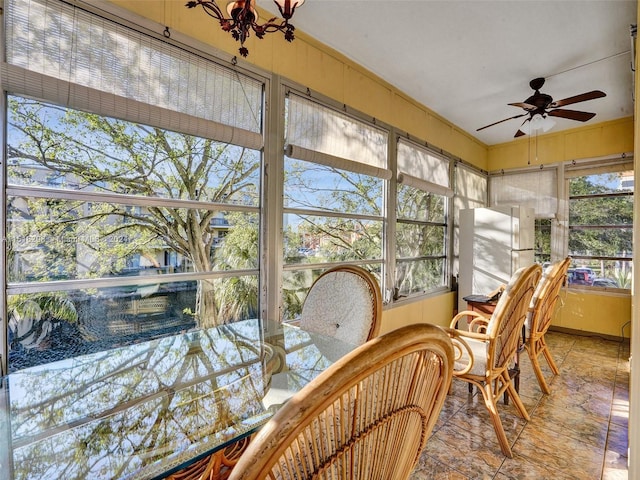 sunroom featuring ceiling fan with notable chandelier