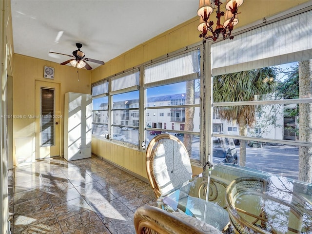 sunroom featuring ceiling fan with notable chandelier