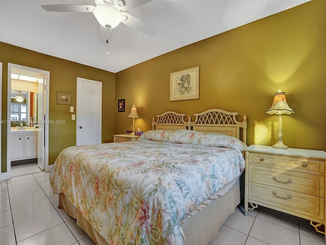 bedroom featuring a closet, ensuite bath, light tile flooring, and ceiling fan