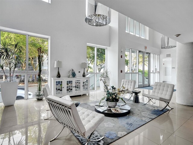 tiled living room with a wealth of natural light, a towering ceiling, and french doors