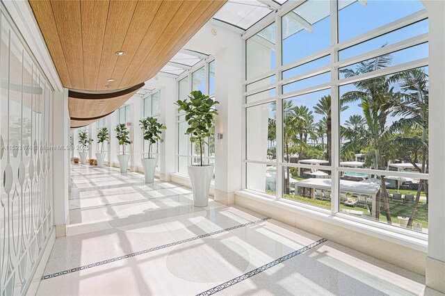 hallway with plenty of natural light and wood walls