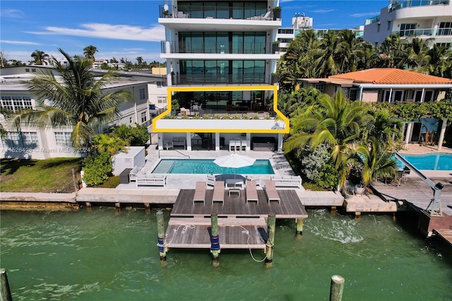 back of house featuring a community pool, a water view, and a patio area