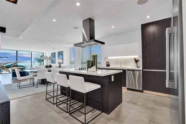 kitchen with white cabinetry, extractor fan, a kitchen bar, a kitchen island, and stainless steel dishwasher