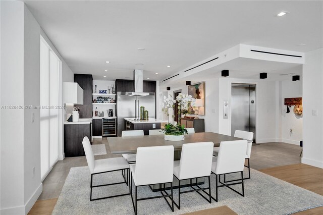 dining space with light hardwood / wood-style flooring, wine cooler, and elevator