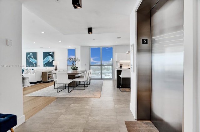 dining area with light hardwood / wood-style flooring, elevator, and floor to ceiling windows