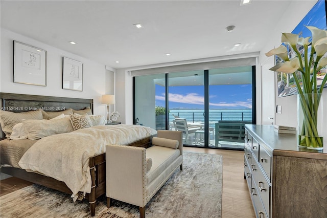 bedroom with light hardwood / wood-style flooring, expansive windows, and access to exterior