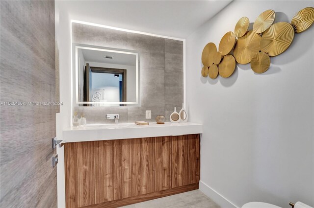 bathroom featuring tile patterned floors, tile walls, toilet, and vanity