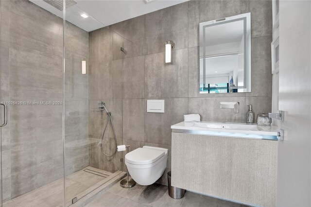 bathroom with toilet, tile patterned flooring, vanity, tile walls, and a shower with shower door