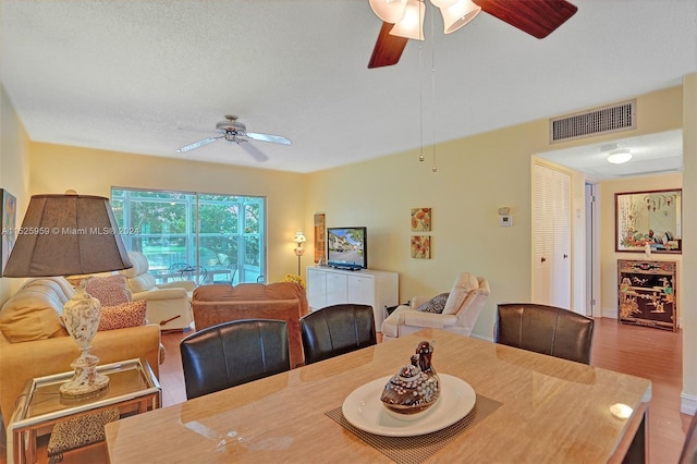 dining area featuring hardwood / wood-style floors, ceiling fan, and a textured ceiling