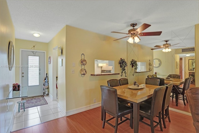 dining space featuring light tile flooring, ceiling fan, and a textured ceiling