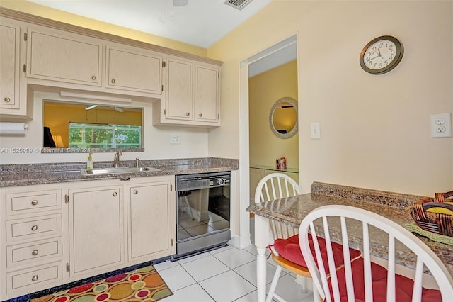 kitchen with light tile floors, dark stone counters, black dishwasher, ceiling fan, and sink