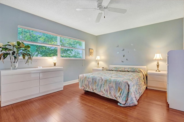 bedroom featuring a textured ceiling, multiple windows, light hardwood / wood-style floors, and ceiling fan