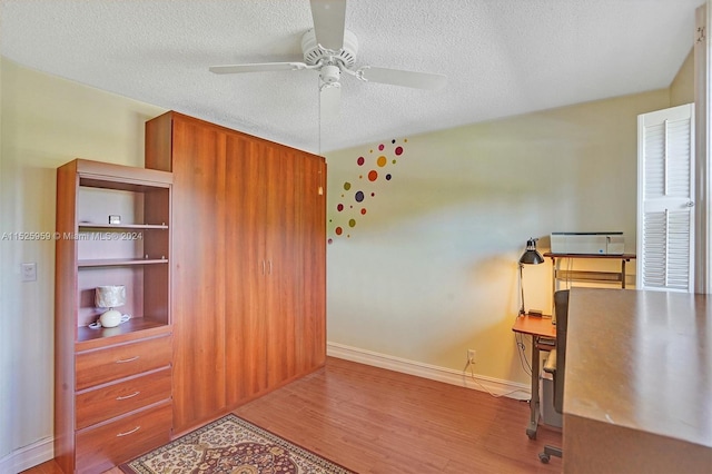 office area featuring built in shelves, a textured ceiling, ceiling fan, and hardwood / wood-style flooring