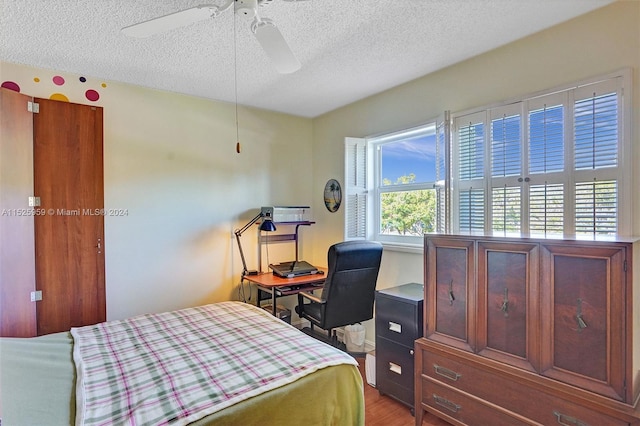 bedroom with hardwood / wood-style floors, ceiling fan, and a textured ceiling