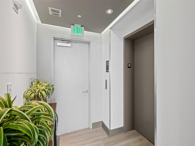 hallway with light hardwood / wood-style flooring and elevator