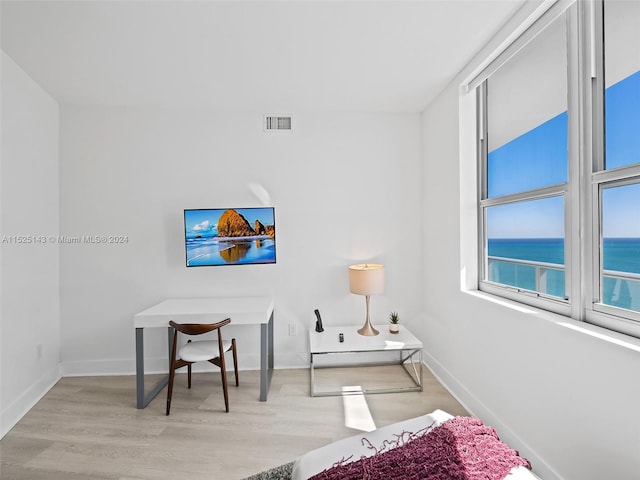 bedroom with a water view and light hardwood / wood-style flooring