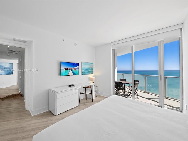 bedroom featuring a water view, access to exterior, and light hardwood / wood-style flooring