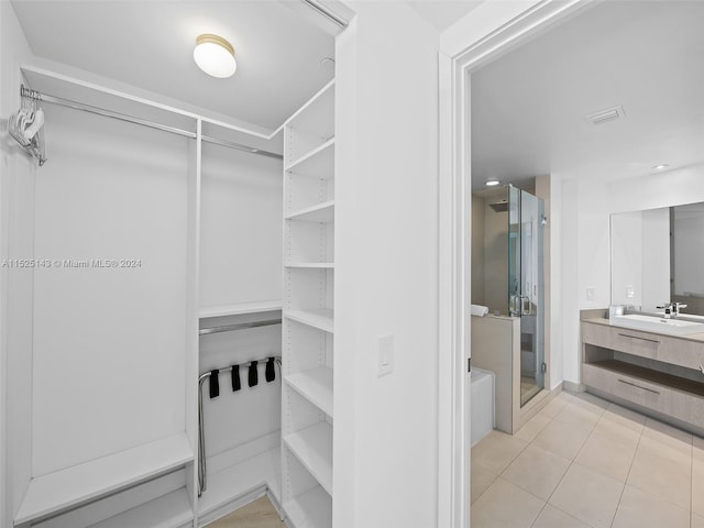 walk in closet with light tile flooring and sink