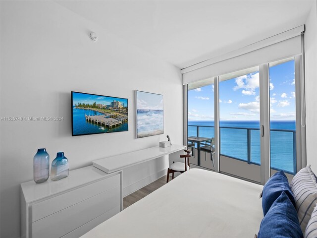 bedroom featuring a water view, access to exterior, and hardwood / wood-style floors