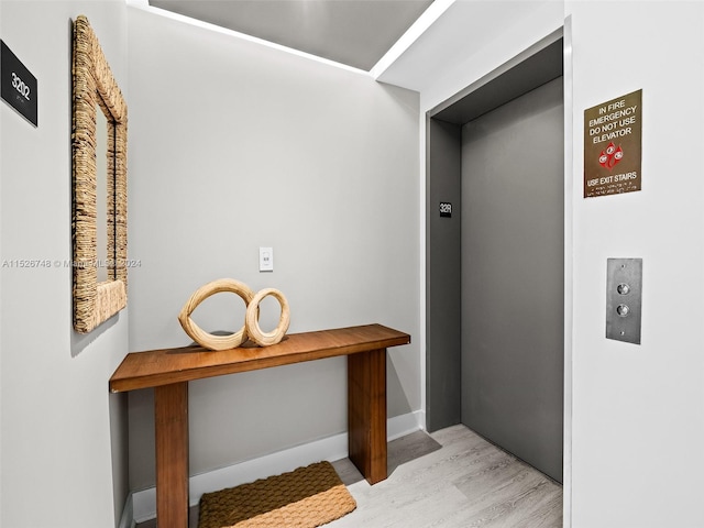 corridor with elevator and light hardwood / wood-style floors