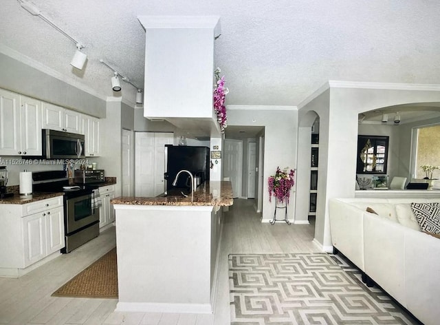 kitchen with a textured ceiling, appliances with stainless steel finishes, white cabinetry, track lighting, and ornamental molding