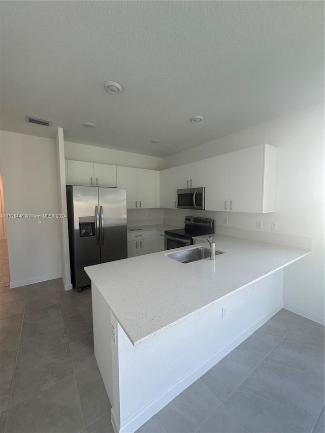 kitchen with white cabinets, stainless steel appliances, kitchen peninsula, and tile patterned floors