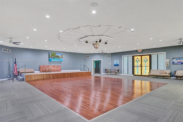 workout room featuring ceiling fan, wood-type flooring, and a textured ceiling