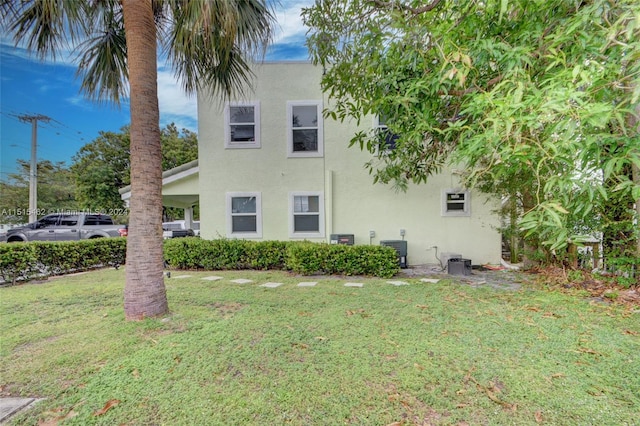 back of property with a yard and central air condition unit