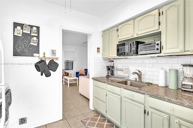 kitchen featuring light tile floors, green cabinets, stone counters, backsplash, and sink