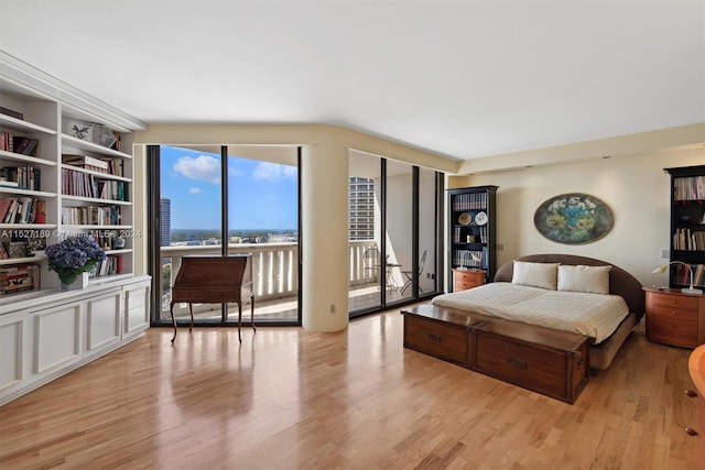 bedroom featuring lofted ceiling, light hardwood / wood-style floors, and access to exterior