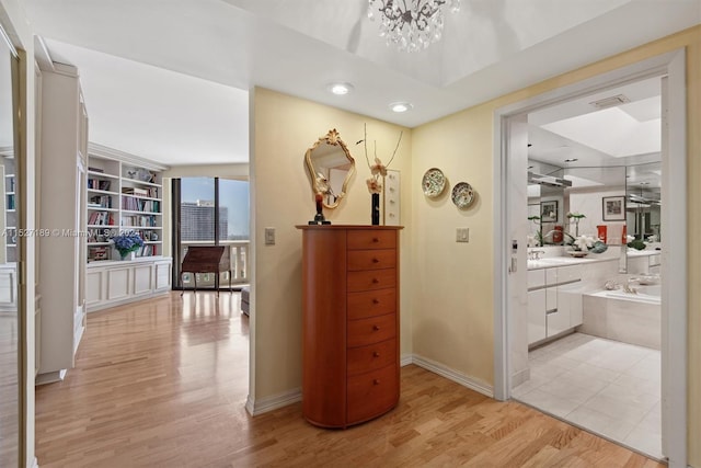 hall with a notable chandelier, sink, and light hardwood / wood-style flooring