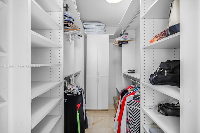 walk in closet with light tile floors