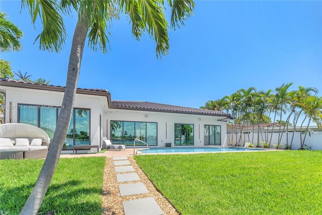 rear view of house with a patio, a fenced in pool, and a yard