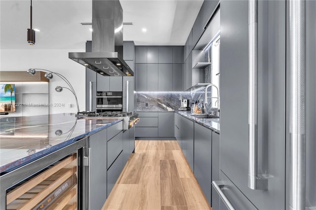 kitchen with sink, appliances with stainless steel finishes, light hardwood / wood-style flooring, fume extractor, and tasteful backsplash